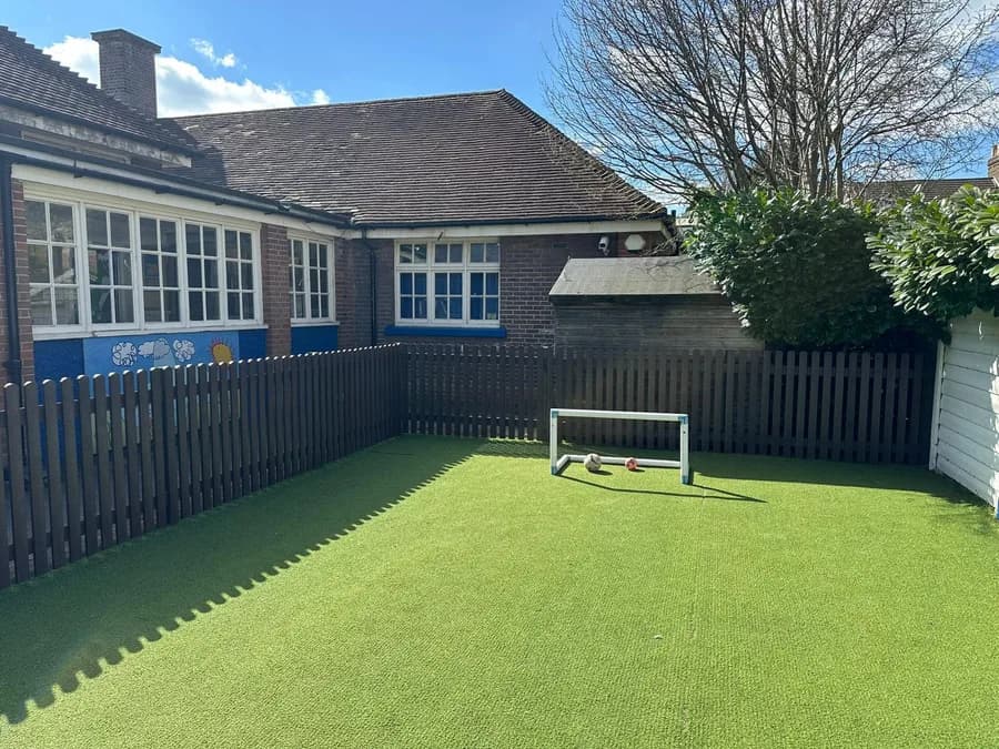 Recycled plastic picket fencing around school playground artificial grass area